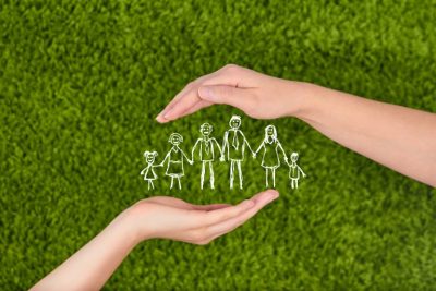 A drawn stick family protected by two hands, life insurance keeping family safe.