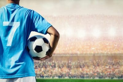 Football player in blue team concept holding soccer ball in the stadium